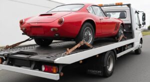 Flatbed tow truck carefully transporting a classic car, highlighting securement methods for safe vehicle transport